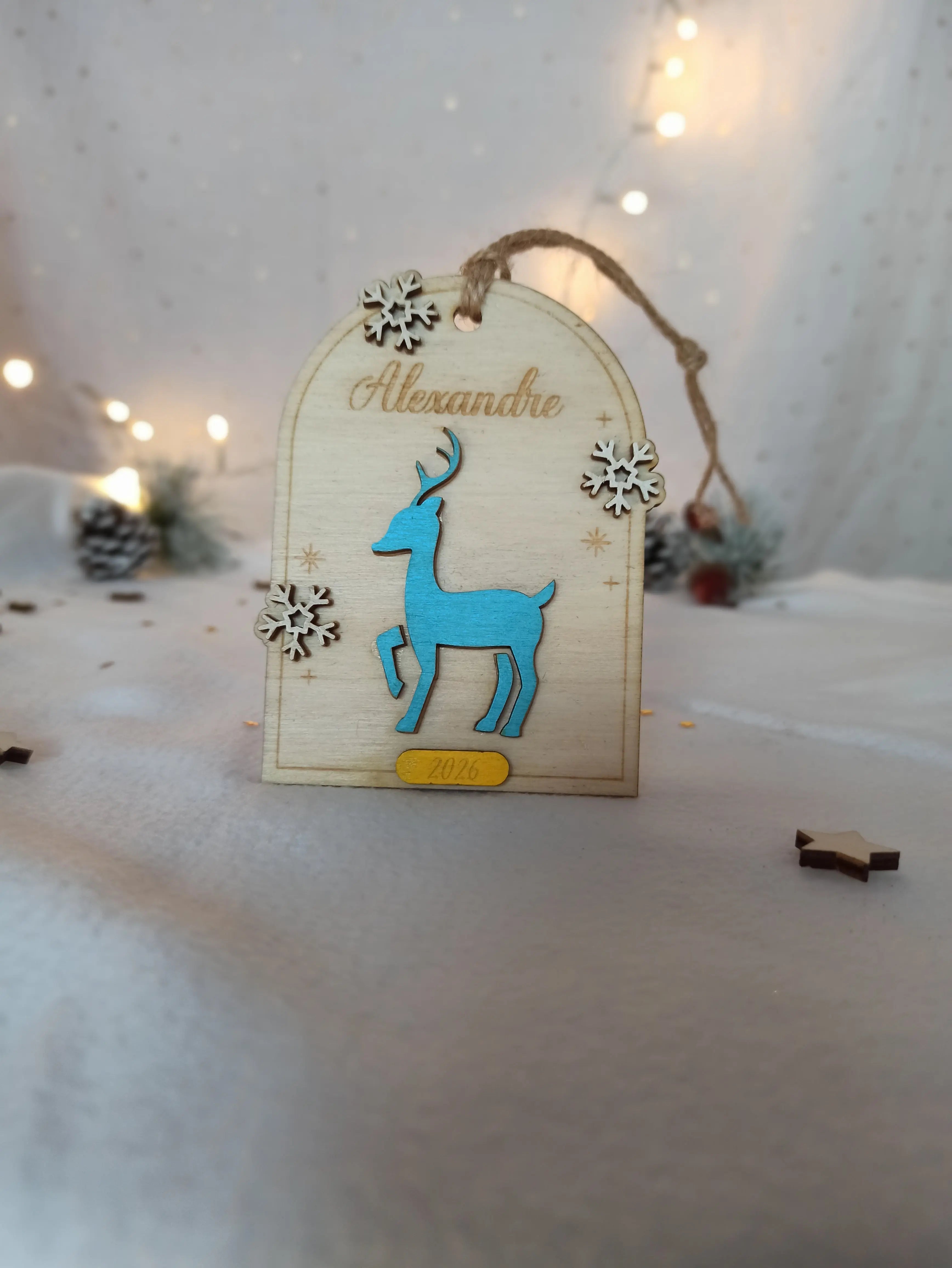 Décoration de Noël personnalisée en bois, modèle “Petit Renne”, avec prénom gravé et petits flocons découpés, style naturel et chaleureux.